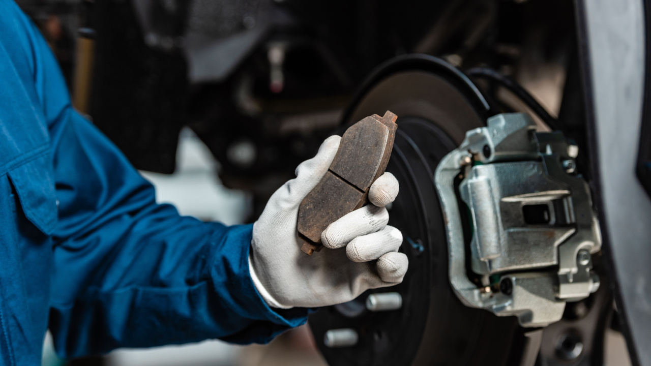 cropped view of mechanic holding brake pad near assembled disc brakes