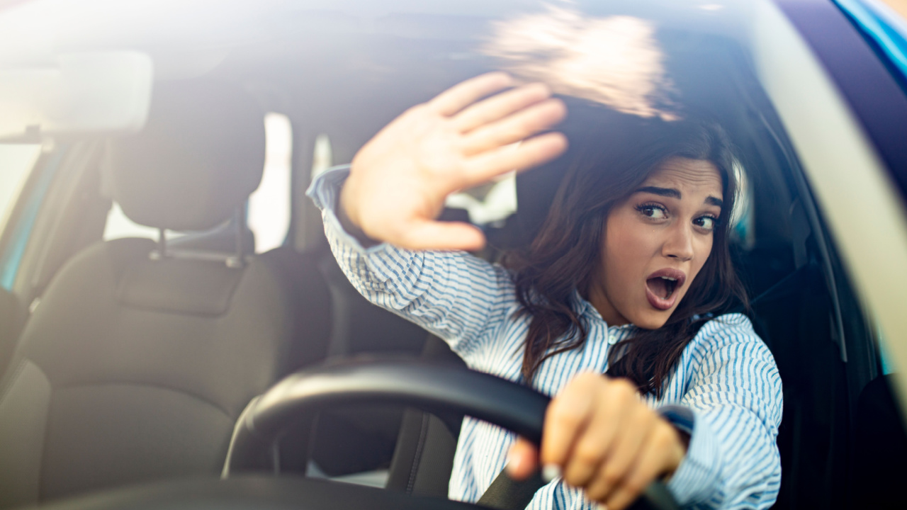 Young terrified woman driving and having a car accident. Mid adult woman driving and looking scared and surprised at the road in front of her. Woman in Car Crash