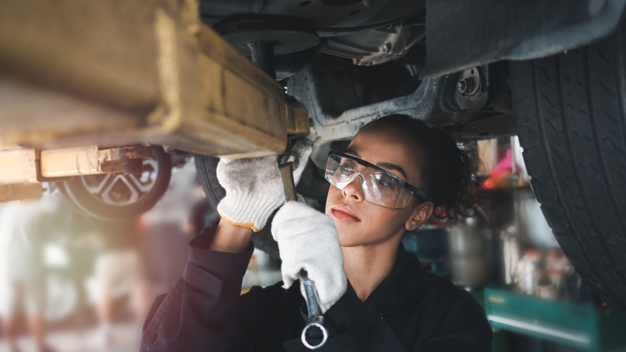 Female auto mechanic work in garage, car service technician woman check and repair customer car at automobile service center, inspecting car under body and suspension system, vehicle repair shop