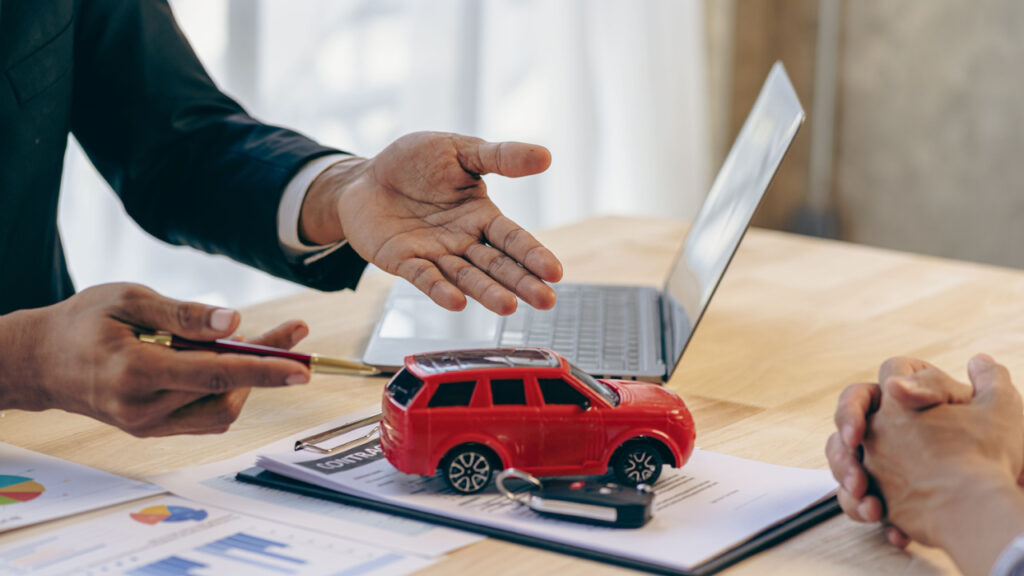 Salesman guiding customer seated at table. Car business. Car sale. Dealership closing. and the new owner has entered into a contract The idea of ​​selling and renting a car with insurance.