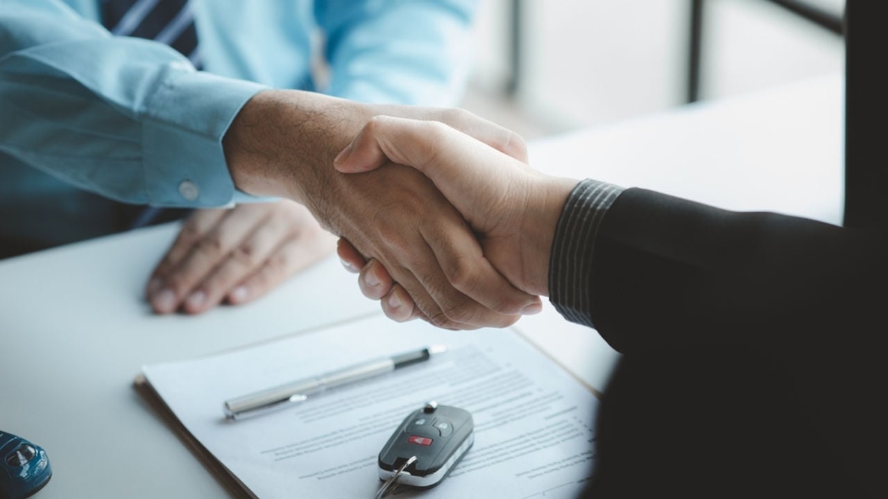 A car salesman is explaining the purchase details and details in the car purchase contract before signing acceptance of the terms, the car sales contract through an agent. Car trading concept.