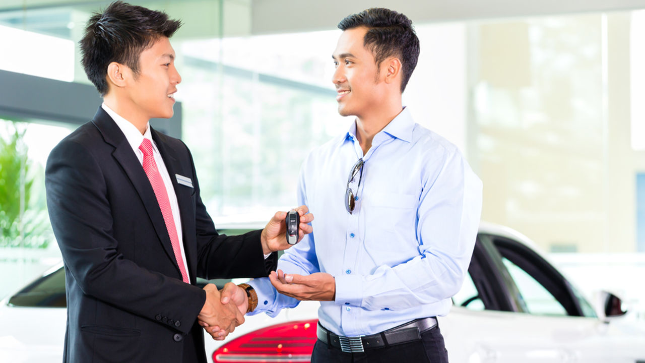 A car salesman is explaining the purchase details and details in the car purchase contract before signing acceptance of the terms, the car sales contract through an agent. Car trading concept.