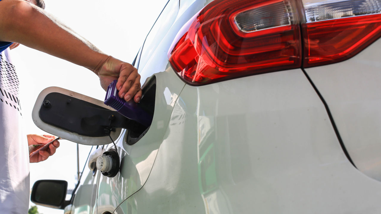 Male employee is adding diesel fuel additive to diesel tank. Increase combustion effciency.