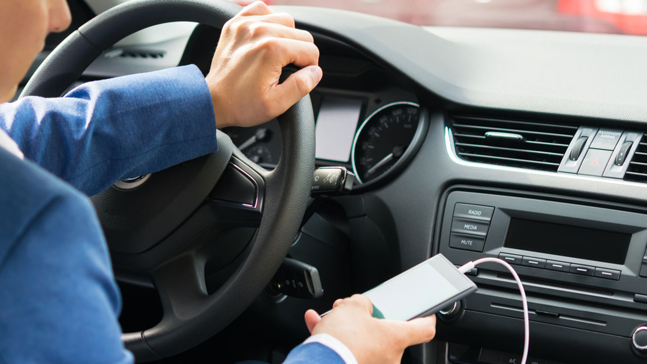 The driver at the wheel of the car turns on the music from the phone