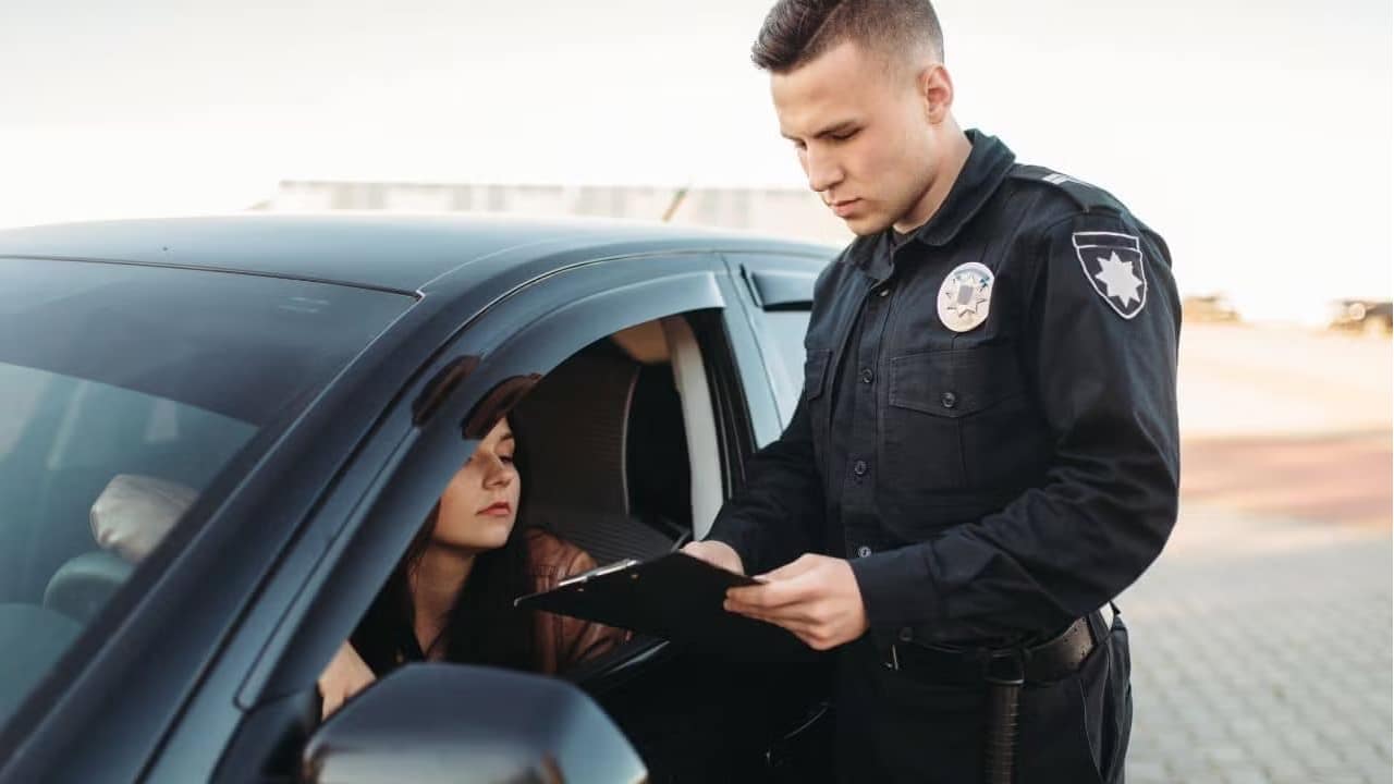 Police officer giving a traffic fine to a woman driving a black car