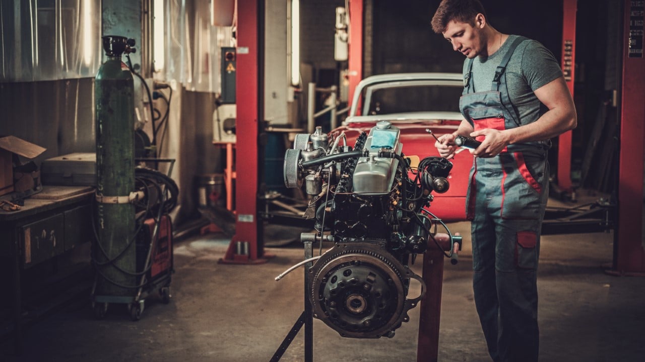 Mechanic,Working,On,Classic,Car,Engine,In,Restoration,Workshop