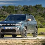 Dacia Duster, front 3/4 view, dark green, forest, dirt on bodywork.