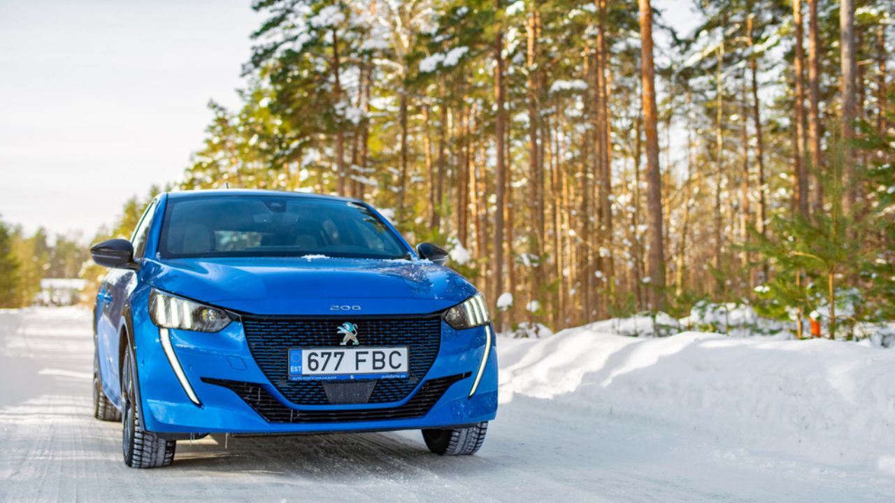 Electric car Peugeot e 208 at the snowy forest road. Sunny winter day.