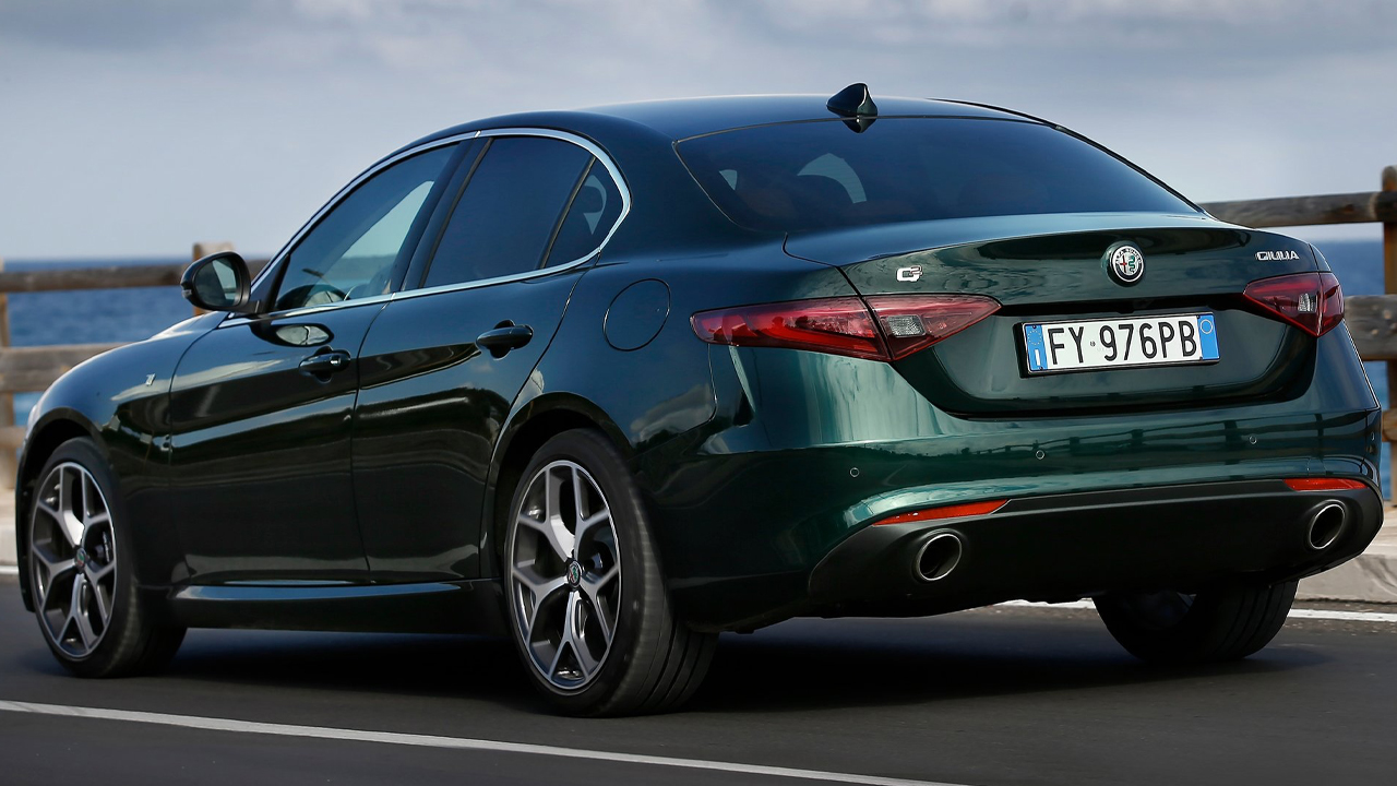 A dark green Alfa Romeo Giulia on the move, rear 3/4 view