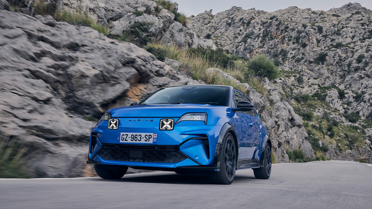 A blue Alpine A290 on the move on a mountain road, front 3/4 view