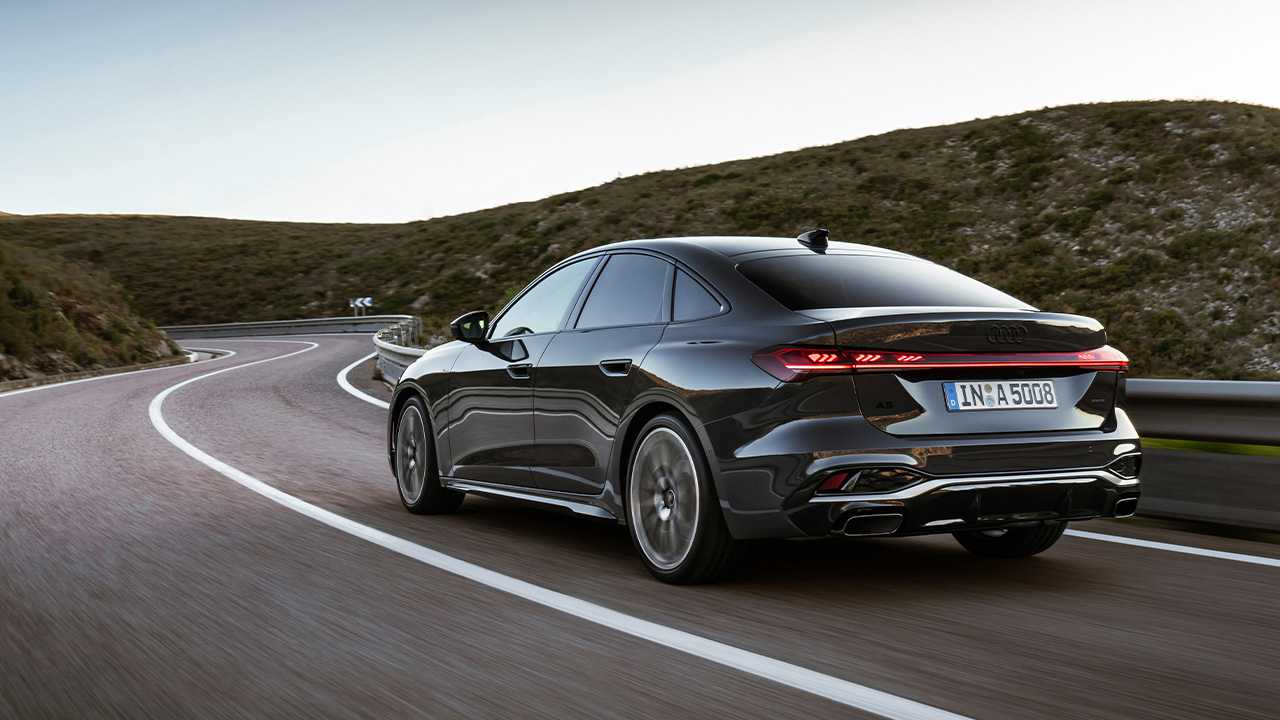 The Audi A5 Sportback in dark gray on the move, rear 3/4 view