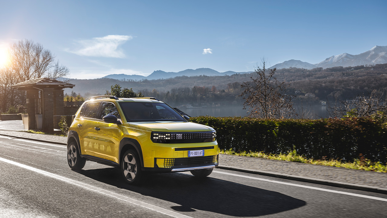 A yellow Fiat Grande Panda on the move, front 3/4 view