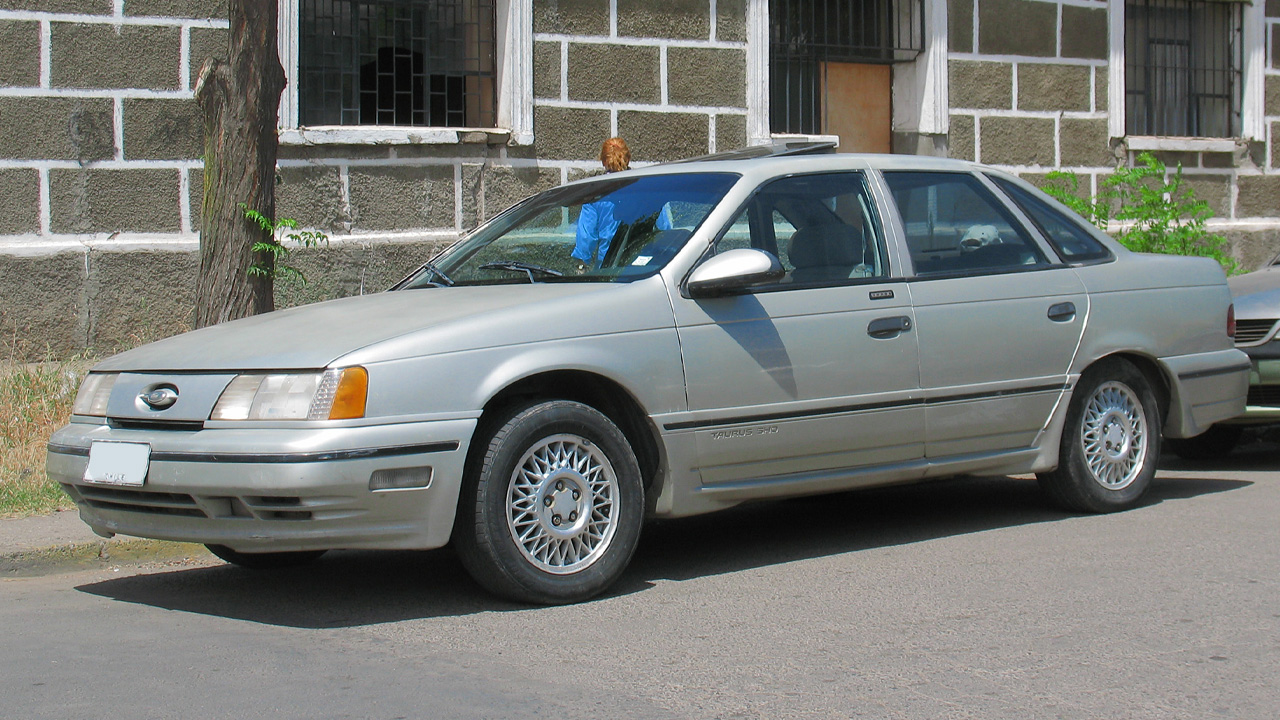 A silver first generation Taurus SHO parked on the street, front 3/4 view