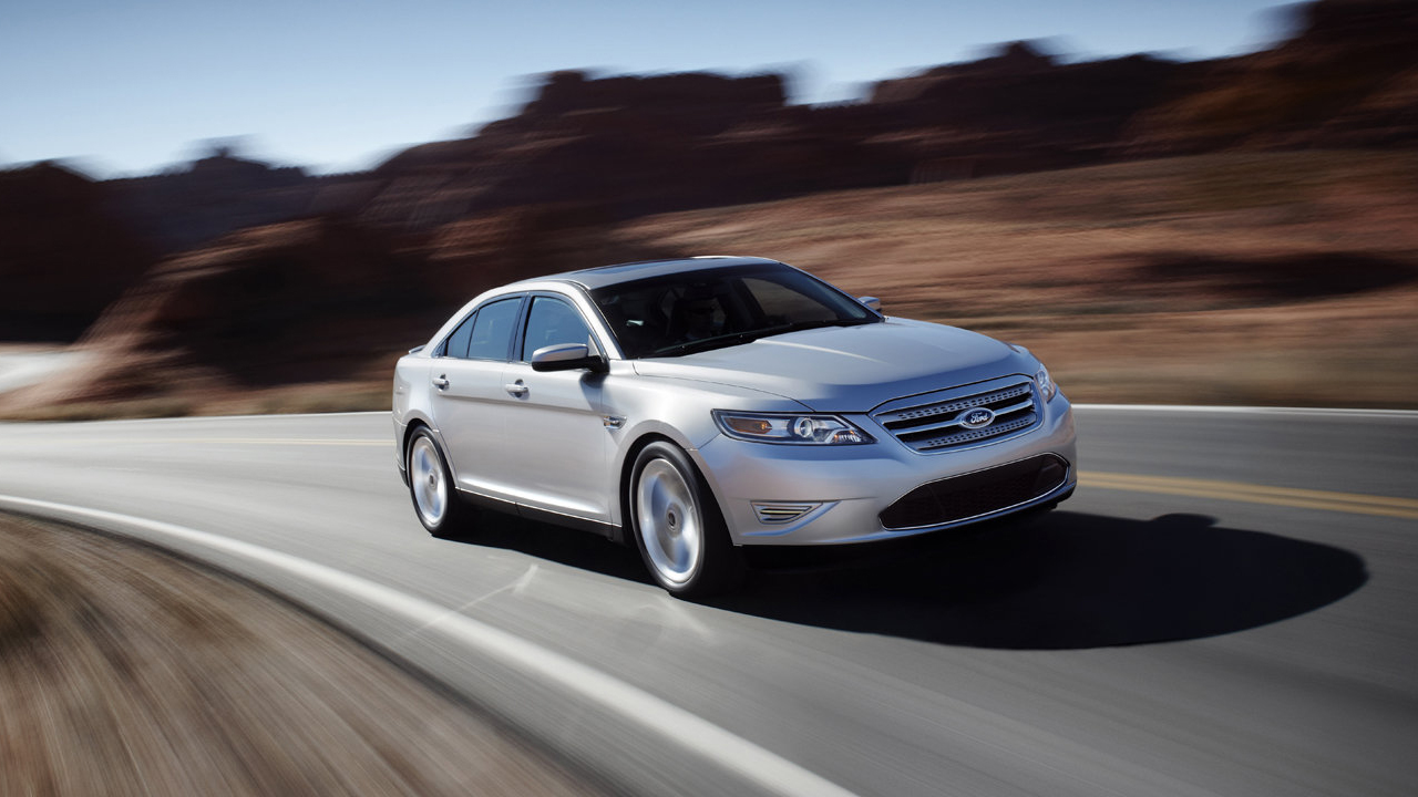 A silver pre-facelift Taurus SHO driving through some canyons, front 3/4 view