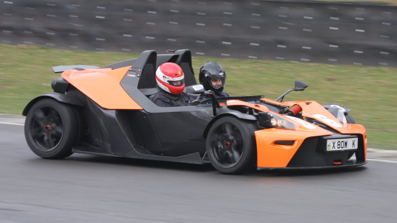 A KTM X-Bow in the signature black and orange on the racetrack, front 3/4 view