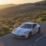 The Porsche 911 Carrera T in white on a mountain road, front 3/4 view, high angle