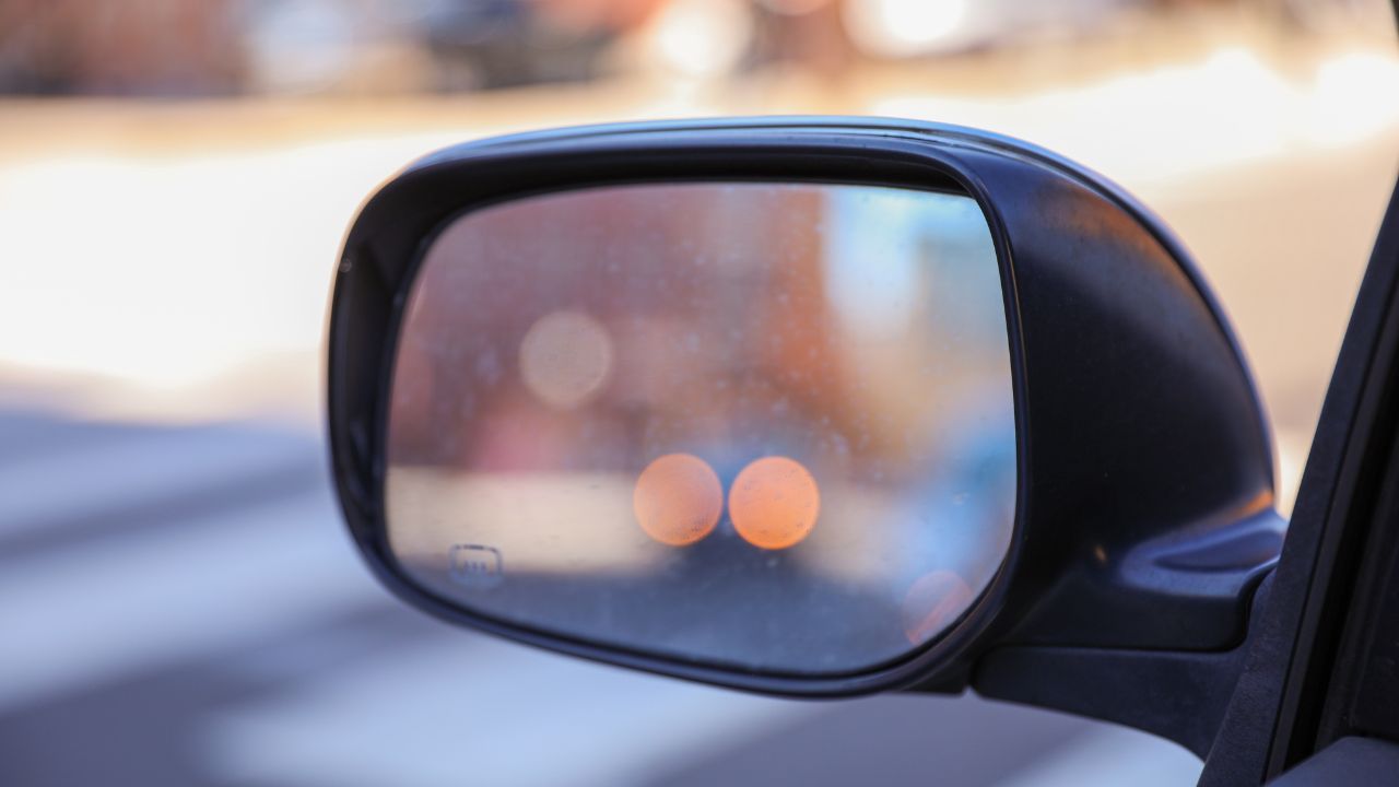 Car mirror in a stock photo symbolizes reflection, perspective, and awareness. It represents the importance of looking back, being mindful of surroundings, and gaining insights from past experiences 