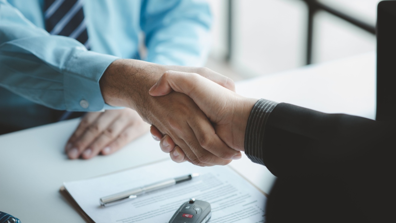 A car salesman is explaining the purchase details and details in the car purchase contract before signing acceptance of the terms, the car sales contract through an agent