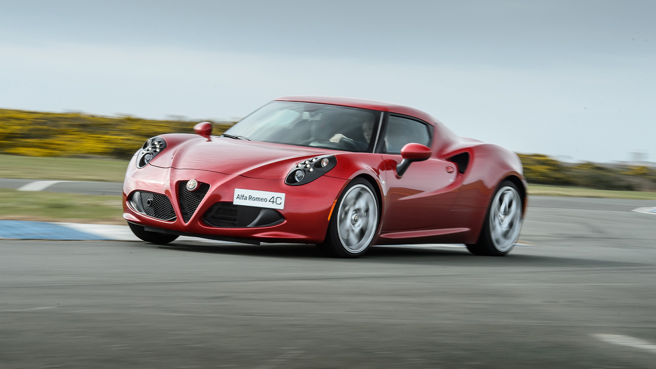 A red Alfa Romeo 4C taking a corner on a racetrack, front 3/4 view