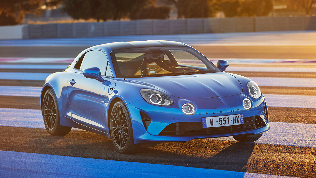 A blue Alpine A110 on the racetrack during sunrise, front 3/4 view