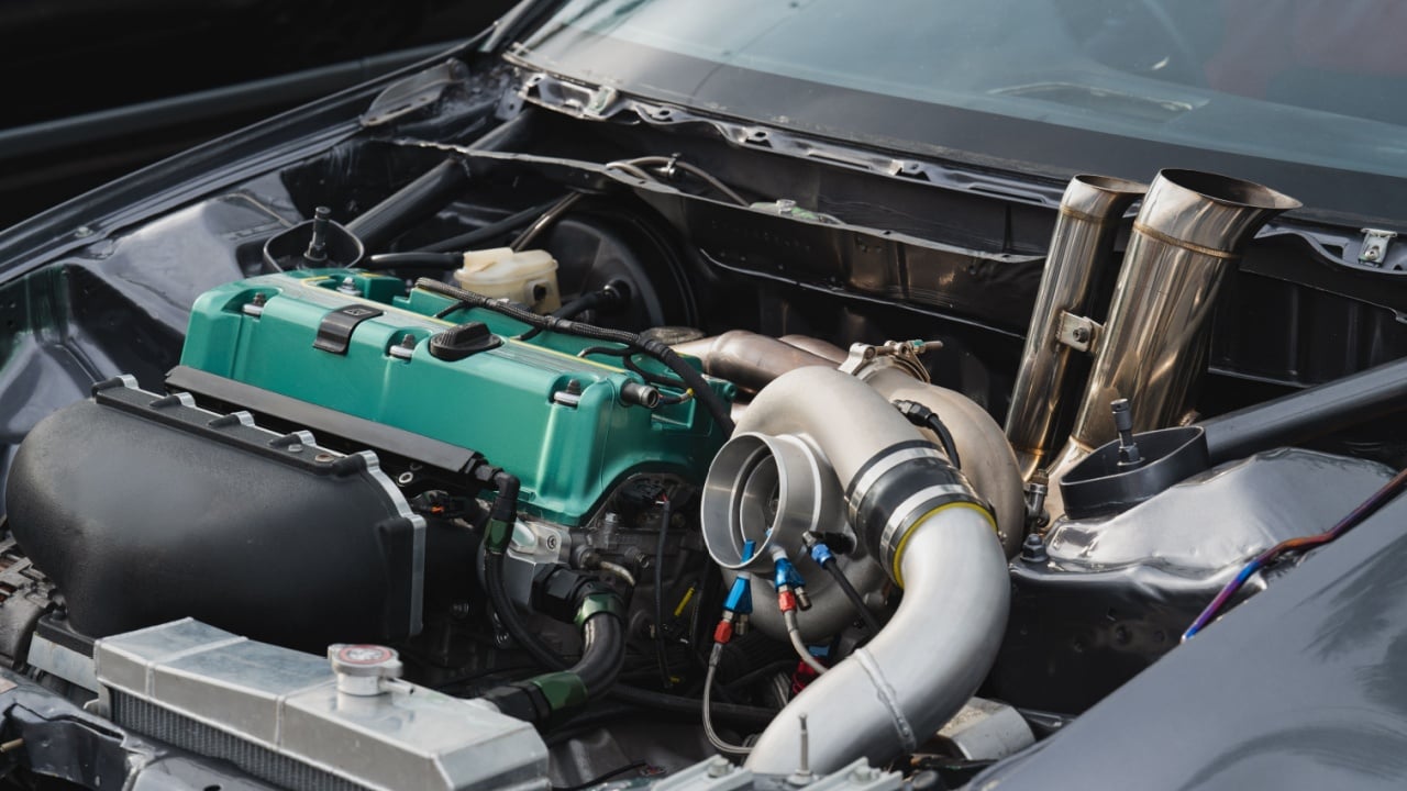 Close-up view of modified car engine, vibrant green valve cover, turbocharger, and intricate piping Ideal for automotive enthusiasts and performance vehicle projects