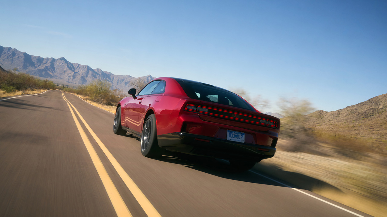 A red Dodge Charger Daytona on the move, rear 3/4 view