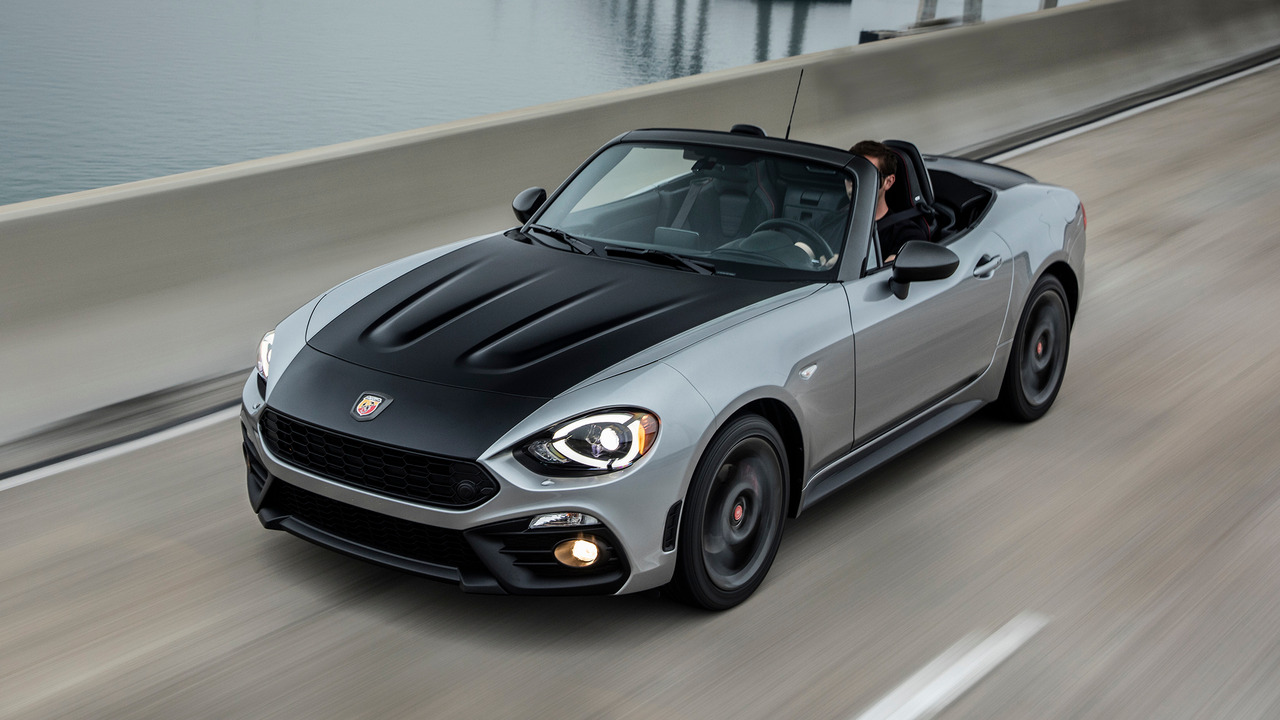 Gray 2019 Fiat 124 Spider Abarth With Matte Black Hood On The Move With Lights On And Roof Down Front 3/4 View