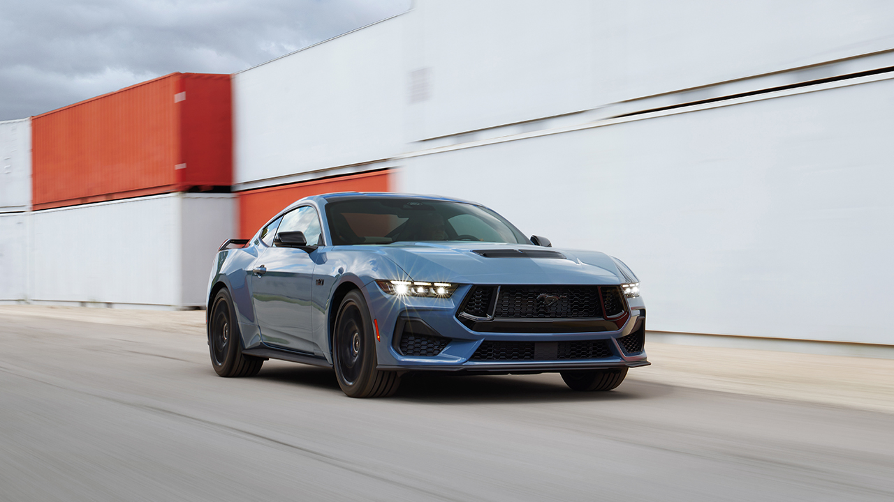 The new Ford Mustang GT in bluish gray on the move, front 3/4 view