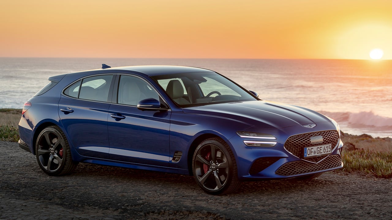The Genesis G70 Shooting Brake in blue, front 3/4 view, sunset
