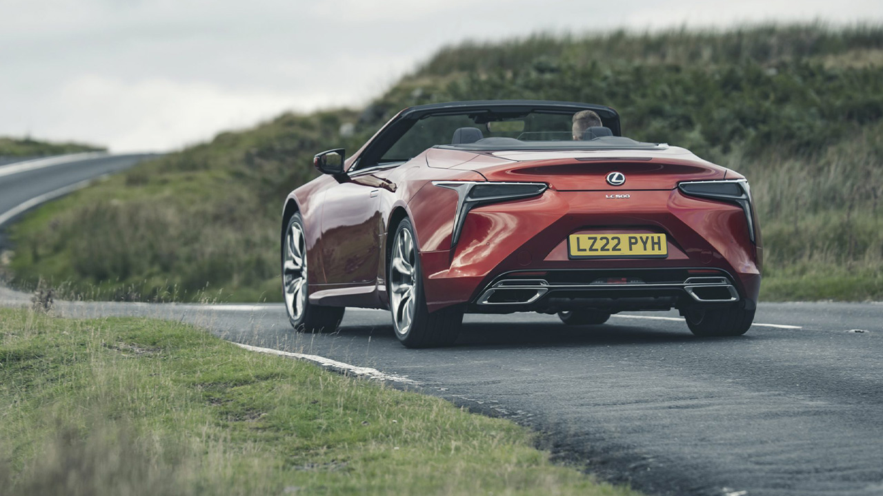 A Lexus LC500 Convertible in red on the move, rear 3/4 view