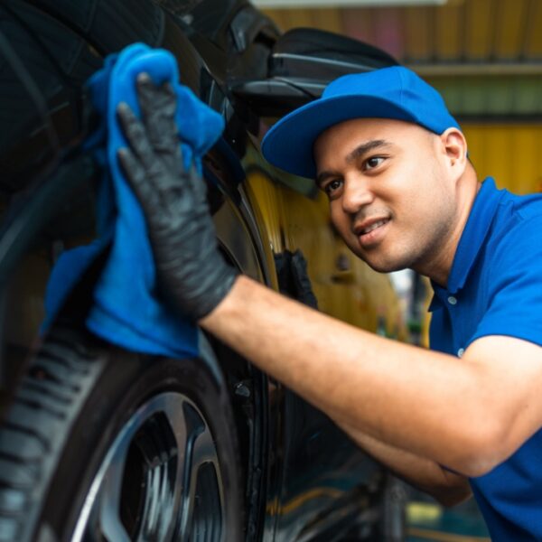 Man worker washing car service with micro fiber. Car wash cleaning wipe station. Employees clean a vehicle professionally detailing.