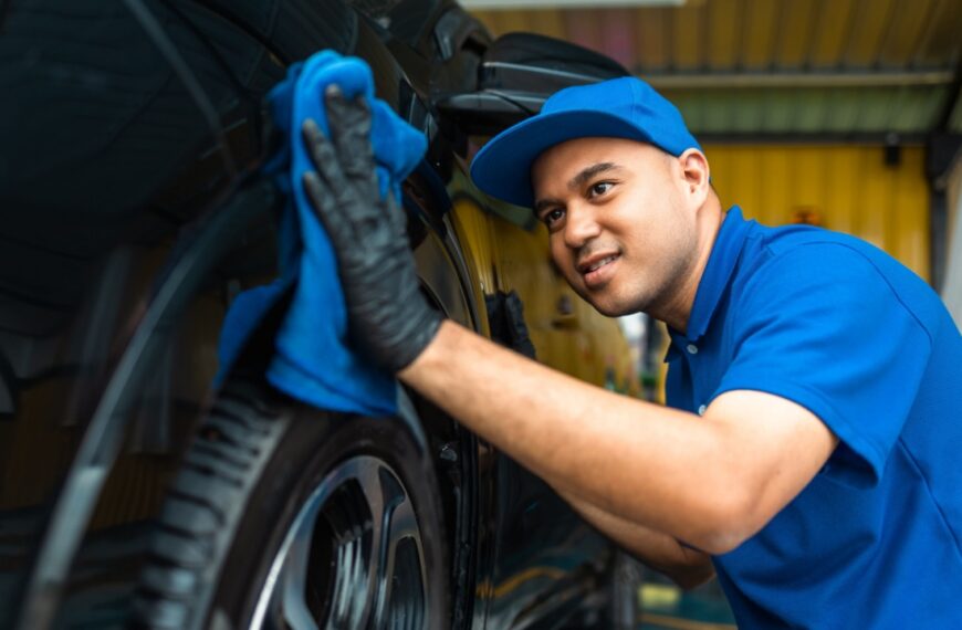 Man worker washing car service with micro fiber. Car wash cleaning wipe station. Employees clean a vehicle professionally detailing.