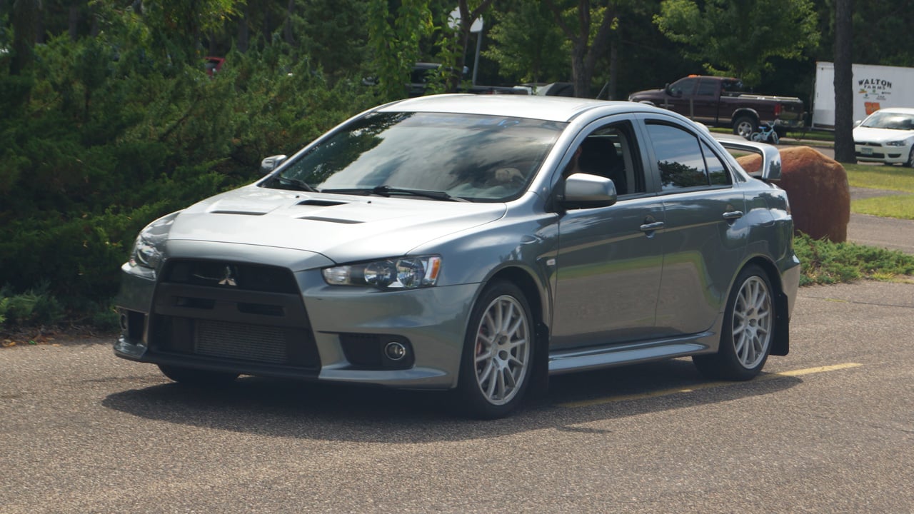 A Mitsubishi Lancer Evo X on the move, front 3/4 view, gray exterior