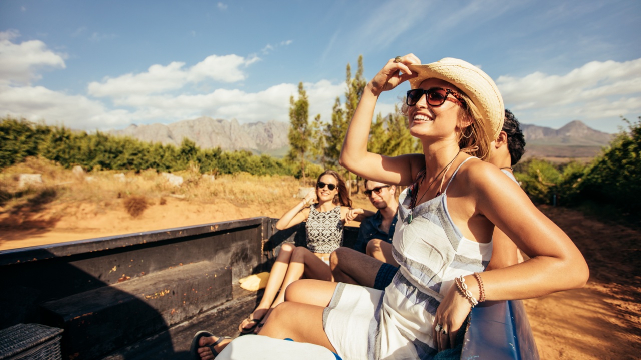 Portrait of happy young friends sitting in a pickup truck going on a road trip