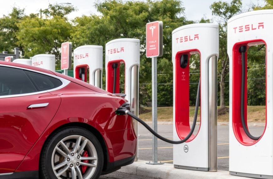 Rear of red Tesla Model S while charging at Tesla Supercharger Station