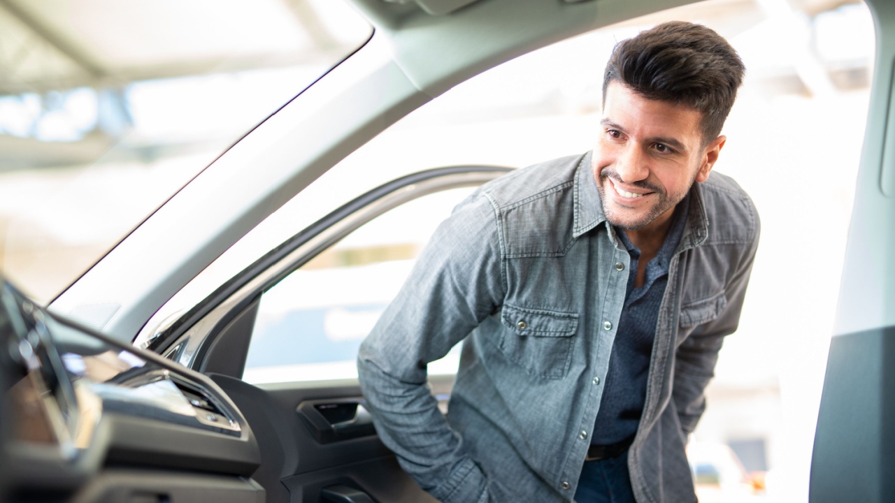 Smiling man searching for a new car in car dealership