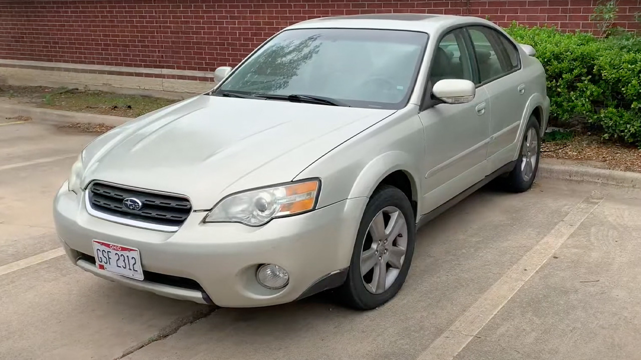 A Subaru Outback Sedan in silver, front 3/4 view, parking lot