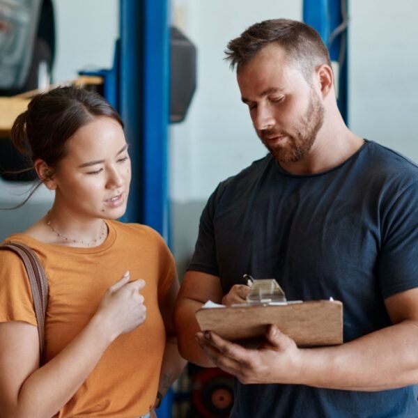 Woman, mechanic and sign quote in auto repair