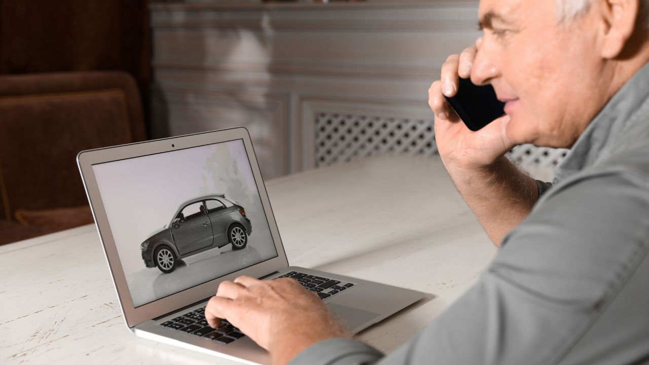 Man using laptop to buy car at table indoors