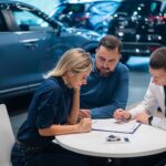 Happy caucasian couple signs a contract for the purchase of a car salon.