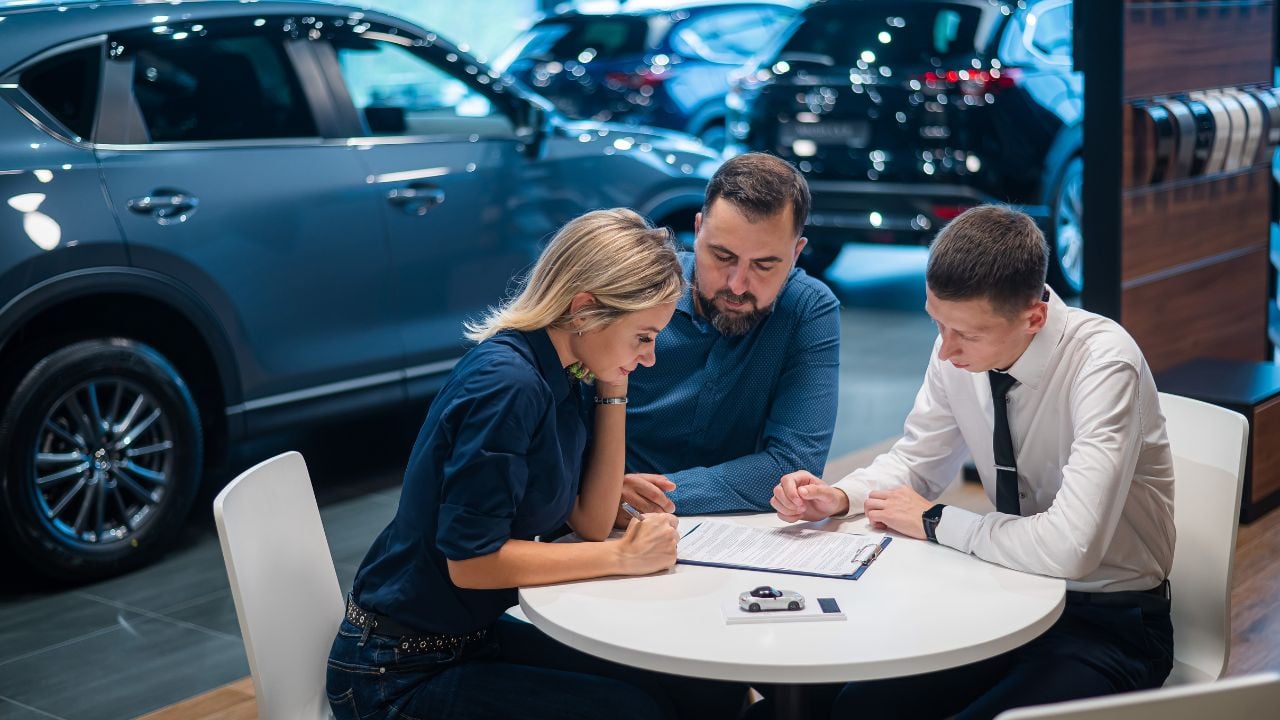 Happy caucasian couple signs a contract for the purchase of a car salon.
