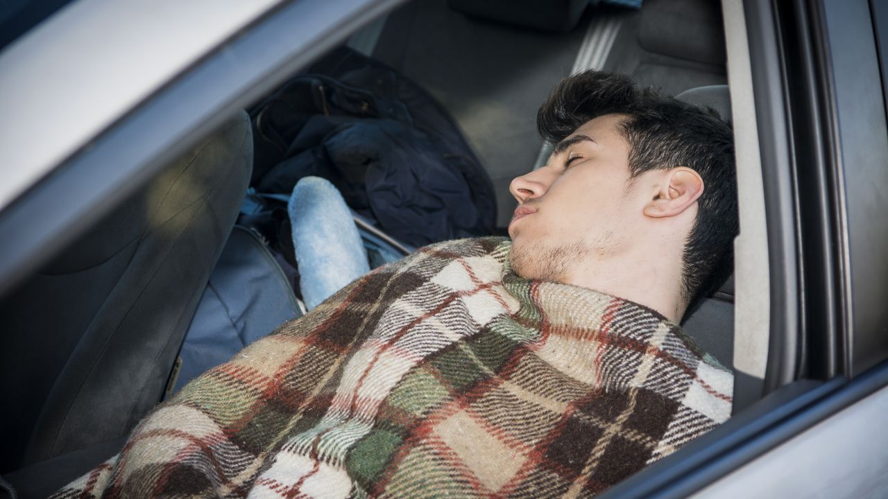 Young handsome man sleeping inside his car, exhausted, tired