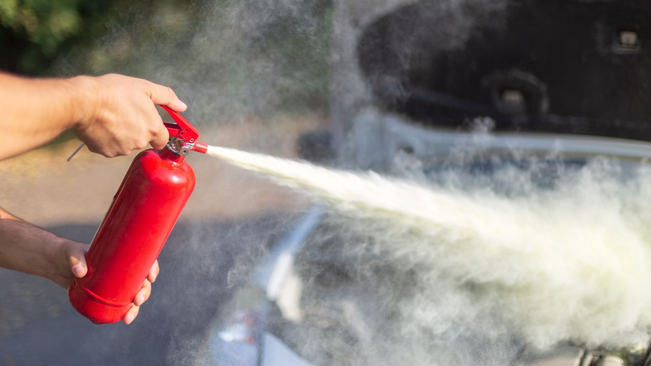 A man that use a fire extinguisher to turn off the fire from the car engine