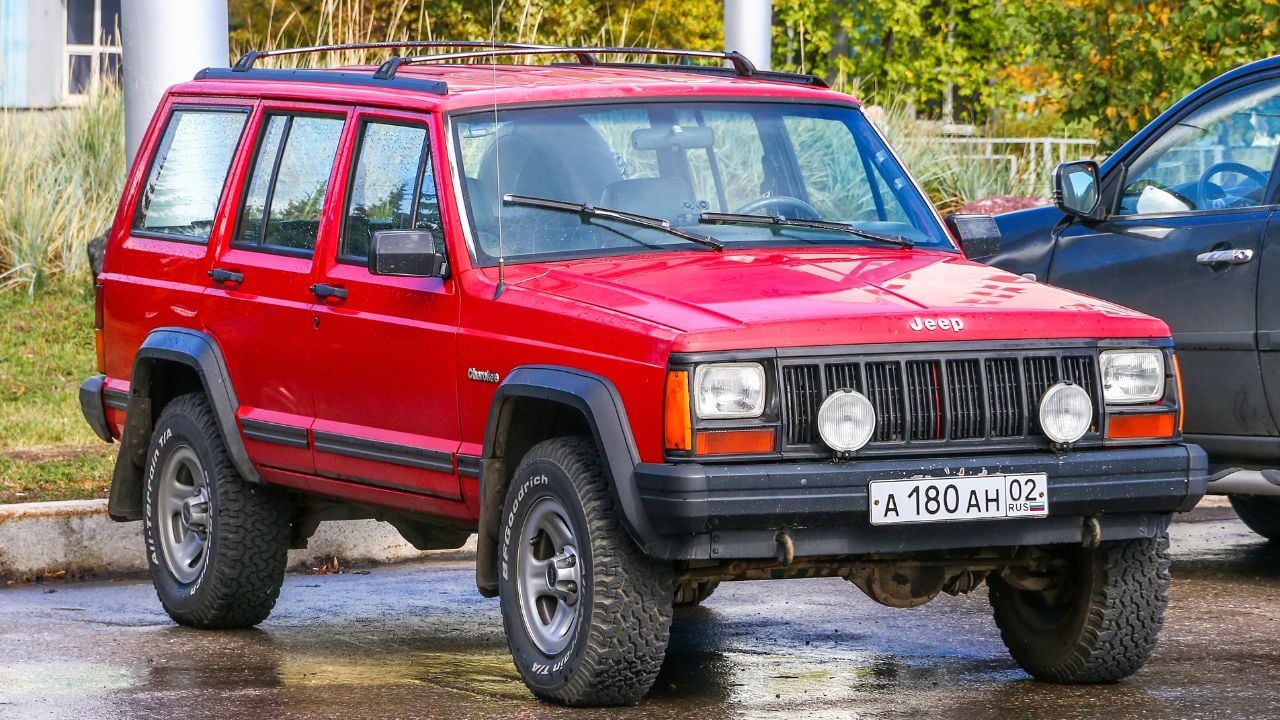 Red offroad vehicle Jeep Cherokee (XJ) in the city street.