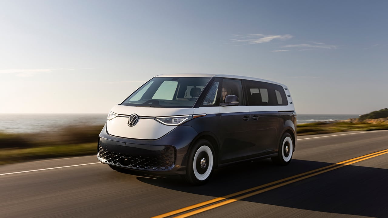 The Volkswagen ID.Buzz in white over dark blue on the move, front 3/4 view