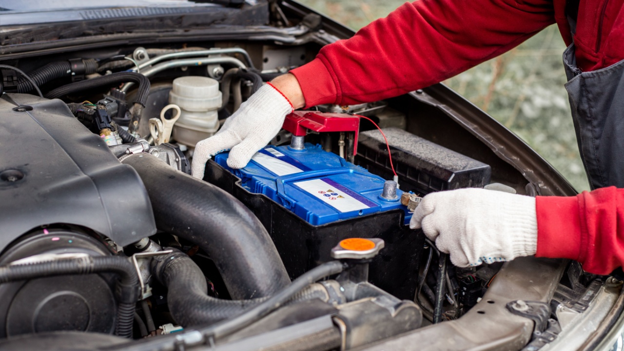 a car mechanic installs a battery in a car