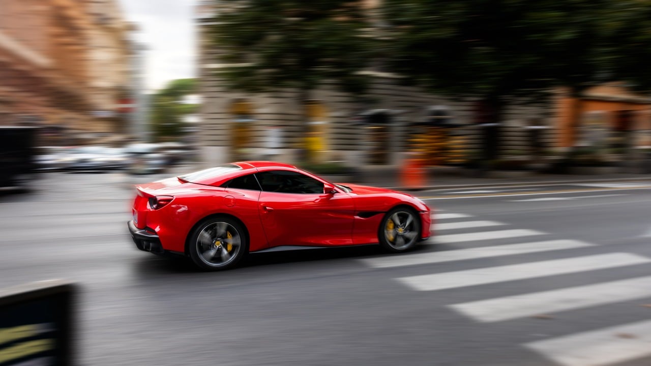Red sports car speeding down a street in Rome