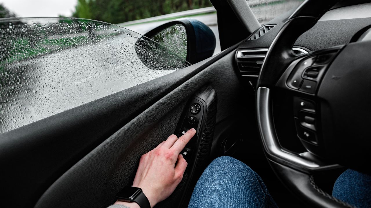 man closing car window in rain