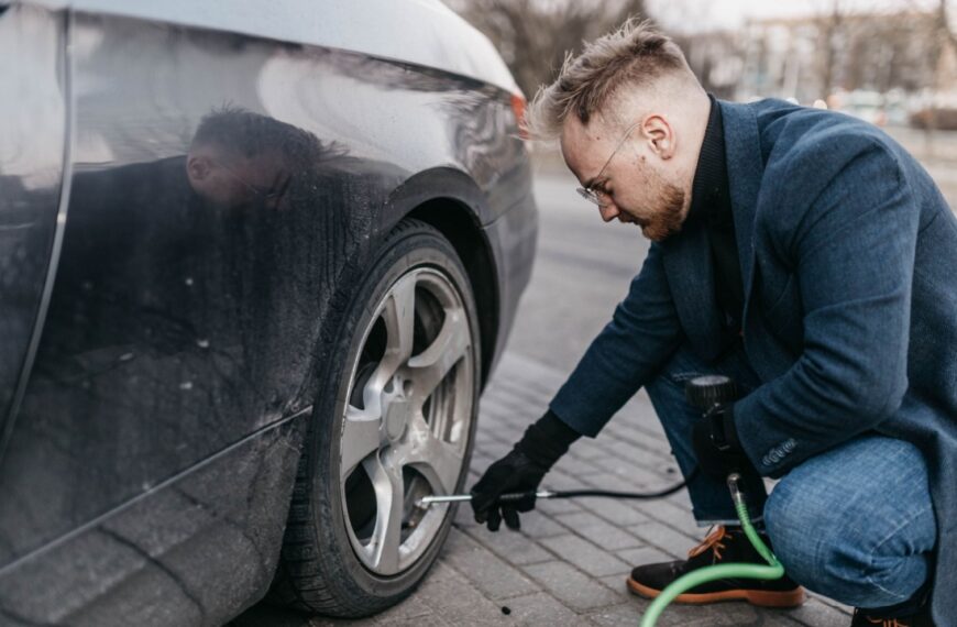 man pumps up the wheels of the car with a compressor.