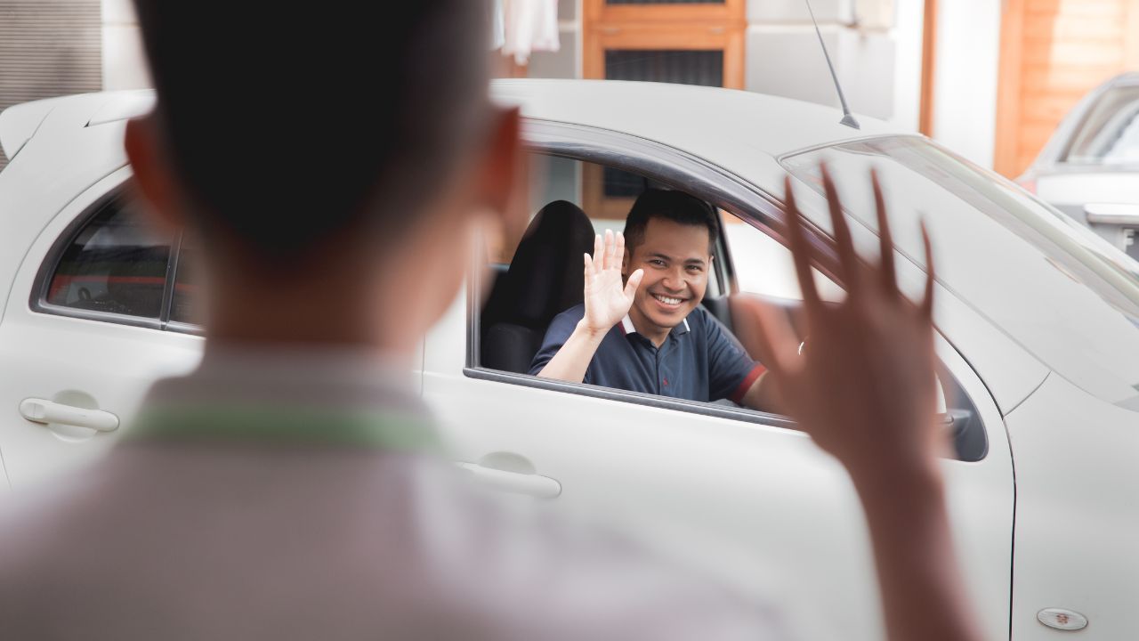 man waving goodbye from car